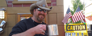 A man in a cowboy hat holding a cup.