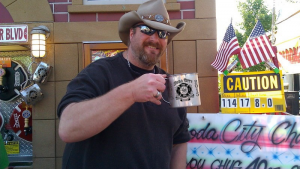 A man in a cowboy hat holding a mug.